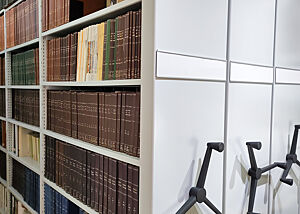 Eine Reihe historischer Fachbücher in verfahrbaren Bibliotheks-Regalen.