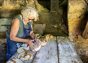 Roswitha Huber hat ein fertig gebackenes Brot umgedreht und inspiziert den Boden.