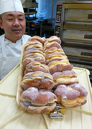Herr Ihara mit gefüllten Knoten. Herr Ihara steht vor einem Tablett mit gefüllten Knoten.