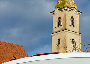 Turm der zum Kloster gehörenden Franziskanerkirche. Der Turm einer Franziskanerkirche ragt in den blauen Himmel.