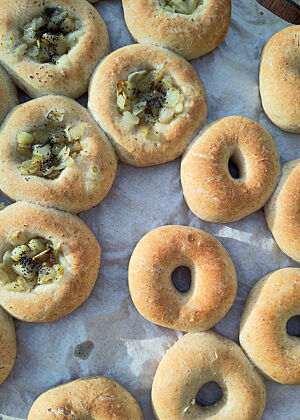 Bialys und Bagels beim Auskühlen in Angelas Garten. Die fertig gebackenen Bialys und Bagels liegen auf Backpapier.