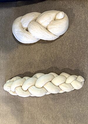 Auf dem Bild sind ein Einstrangzopf und ein Vierstrangzopf auf einem mit Backpapier ausgelegten Backblech zu sehen. 