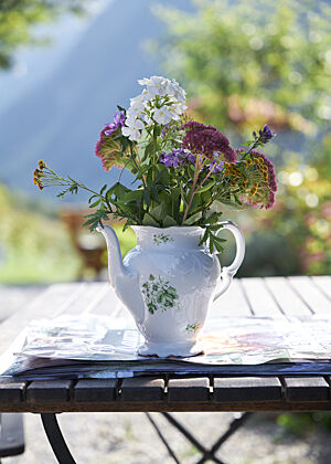 Eine hohe Teekanne wurde als Vase für Blumen umfunktioniert.
