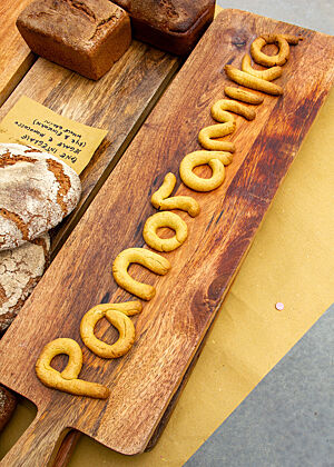 … beim Brotfest gebacken Ein Tisch mit verschiedenen Brotsorten, u.a. ein Brett mit dem Schriftzug "Panoramika" aus Teig.