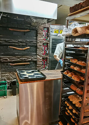 Andere Bäckerei, ähnliches Konzept. Gebacken wird ganz oft vor den Augen der Kunden. Ein Blick in die Backstube einer Bäckerei: Bereits gebackene Gebäckstücke warten in einem Wagen auf den Weitertransport in den Verkaufsraum.