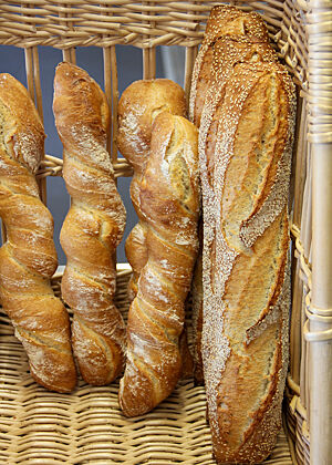 Baguettes und Wurzelbrote stehen ein einem Baguettekorb.