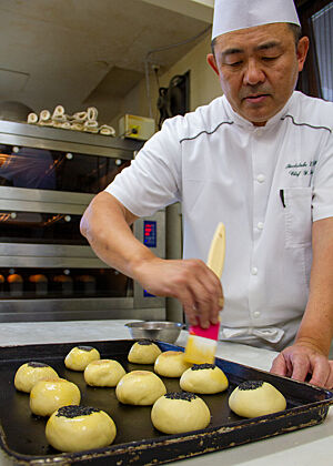 Herr Ihara streicht die gefüllten Anpans mit Ei ab.