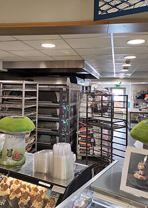 Die In-House-Bäckerei Bácús im SuperValue-Supermarkt in Dingle. Blick über die Verkaufstheke in die Backstube mit dem Etagenofen und den Knetmaschinen im Hintergrund.