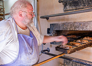 Günther Weber prüft das Backgut. Der Bäckermeister Günther Weber prüft die Körnerbrote in den Kastenformen, ob sie schon fertig gebacken sind.