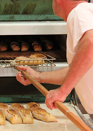 Die goldbraun ausgebackenen Sandwich-Brote werden mit einem großen Schieber aus dem Ofen geholt.
