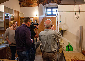 Die Schwarzküche im Franziskanerkloster gefüllt mit Fernsehteam, Dolmetscher und Bäckern. Ein Kamerateam filmt in der Küche des Klosters.