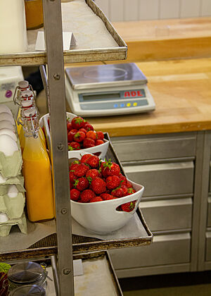 Auf dem Regal einer Backstube stehen Erdbeeren, Eier und weitere Zutaten.