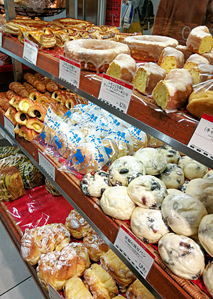„Steamed Bread“, also gedämpfte Teiglinge, sind typisch für Japan. Weich und saftig. Helle gedämpfte Brötchen liegen neben anderen Gebäckstücken in der Auslage einer japanischen Bäckerei.