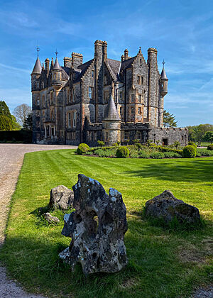 Blarney Castle in Blarney bei Cork. Ein steinernes Gebäude umgeben von grüner Wiese.