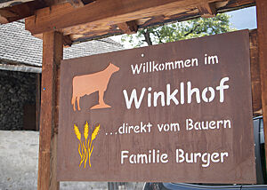 Zu Gast bei Familie Burger in Prad. Ein großes Schild aus Metall heißt den Besucher des Winklhofes bei Familie Burger willkommen.