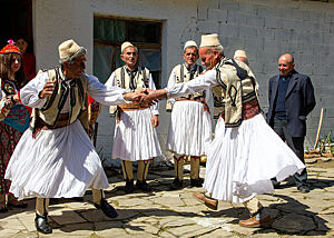 Zwei Schäfern in traditioneller Tracht führen einen Tanz auf.