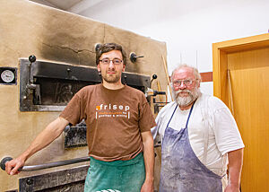 Lutz Geißler und Günther Weber stehen in der Backstube des Lorettohofes in Zwiefalten vor dem Holzofen.