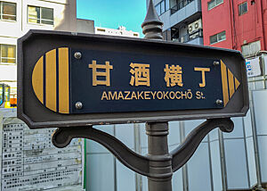 Ein Straßenschild verweist in japanischen und lateinischen Schriftzeichen auf den Amazake.