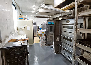 Blick in die Bäckerei Blick am Etagenofen vorbei in die Backstube. Links der Tisch zum Aufarbeiten der Teige, weiter hinten die Kühlung und die Gärschränke.