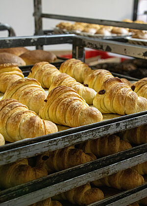 Auf Blechen liegen goldbraun gebackene Croissants, welche von Giovanni genau wie die Brote im Holzofen gebacken werden.