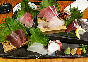Sashimi zum Abendessen. Appetitlich angerichtetes Sashimi liegt auf einem schwarzen Brett.