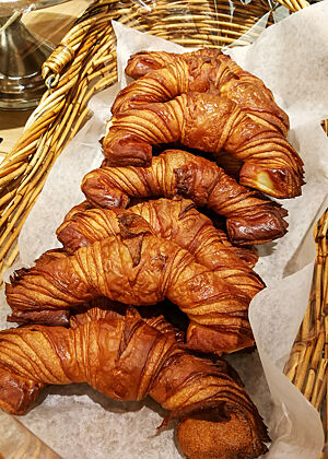 Lange Croissants mit breiten Enden liegen in der Auslage einer Bäckerei.