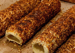 Der echte Trdelník nach dem Backen. Die goldbraun ausgebackenen und bereits von der Holzstange abgezogenen Skalický Trdelník wurden in Walnussstückchen gewälzt.