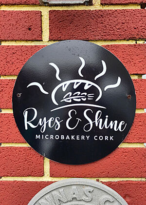 Türschild an der Bäckerei von Angela Nöthlings. Schild mit der Aufschrift „Rye's & Shine Microbakery Cork“.
