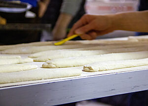 Die geformten und gereiften Baguette-Teiglinge werden im flachen Winkel mit einer Rasierklinge eingeschnitten.