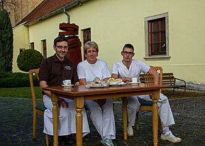 Lutz, Martha und Lukas sitzen am mit Kaffee und Skalický Trdelník gedeckten Tisch.