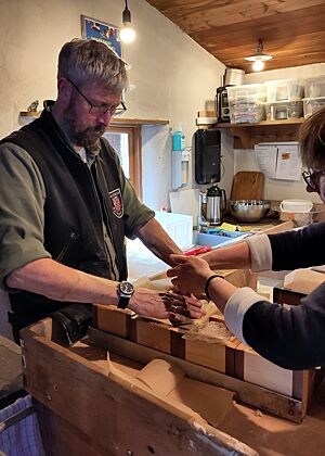 Helfende Hände beim Befüllen der Rahmen Harald hält das Backpapier in den Holzrahmen auseinander, damit Sibylle besser die Teiglinge platzieren kann.
