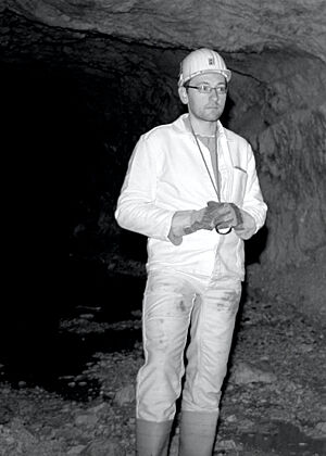 Ein Geologe in weißer Schutzkleidung steht aufrecht im Stollen.