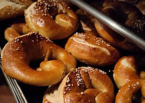 Goldbraune, glänzende Kruste Die goldbraun ausgebackenen Brezeln haben eine glänzende Kruste und liegen auf einem Blech zum Auskühlen an der frischen Luft.
