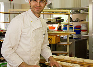 Während der Ofen nochmals aufgeheizt wird, dreht Ricardo Fischer seine Zwirbelbaguettes beim Schaubacken. Bäckermeister Ricardo Fischer dreht Zwirbelbaguettes mit der Hand.