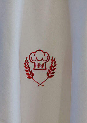Das Emblem der Sendung „Deutschlands bester Bäcker“ zeigt auf weißem Hintergrund zwei rote Ähren, die eine rote Bäckermütze umranden.