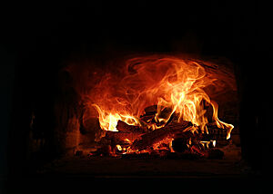Der Holzofen für die Roggenbrote wird angeheizt. Die rot-gelben Flammen erhellen das Innere des Holzofens.