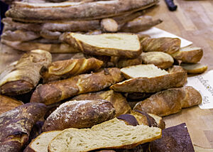 Ein Tisch voller Freuden. Auf einem Tisch liegen kräftig ausgebackene Wurzelbrote und Baguettes.