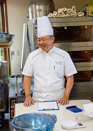 Bäckereichef und Kursleiter Ihara Herr Ihara steht vor seinem Etagenofen und lacht.