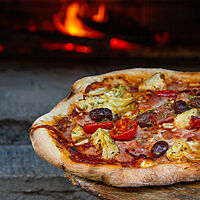 Hüttenpizza mit Anstellgut und Hefe gelockert, frisch aus dem Holzbackofen.