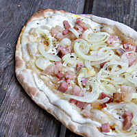 Ein knusprig ausgebackener mit Zwiebeln und Speck belegter Flammkuchen. 