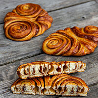 Ein halbiertes Franzbrötchen zeigt die Windungen der Schneckenform und die feinporige, helle Krume.