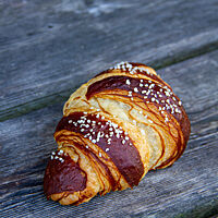 Ein mit Salz bestreutes Laugencroissant liegt auf einem rustikalen Holztisch.