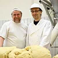 Bäcker Süpke (links) und Lutz (rechts) stehen hinter einem großem Berg von frisch geknetetem Teig.
