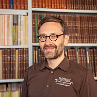 Lutz Geißler steht vor einem Buchregal seiner Brotbuch-Bibliothek.