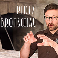 Lutz Geißler mit erklärenden Gesten vor einem Holzbackofen. Im Bild der Schriftzug „Plötz’ Brotschau“