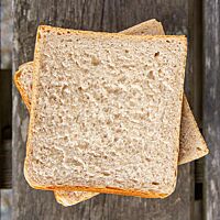 Zwei Scheiben Toastbrot liegen auf einem rustikalen Holzuntergrund.