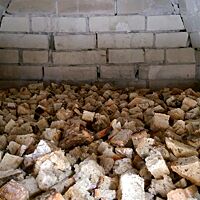 In einem gemauerten Holzofen liegt gewürfeltes Restbrot zur Trocknung für die Weiterverwertung.