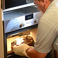 Brotdoc Björn Hollensteiner holt ein gebackenes Brot aus dem Ofen