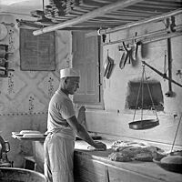 Das Schwarzweißbild von ca. 1920 zeigt den Bäcker Max Lohs beim Wirken eines Teiglings Max Lohs in seiner Backstube im erzgebirgischen Jöhstadt. 