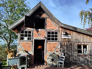 Backhaus in Barrigsen Das Backhaus in Barrigsen ist ein altes Fachwerkhaus mit rotem Klinker. Durch die geöffnete Tür kann man das Feuer im Holzbackofen bereits sehen.
